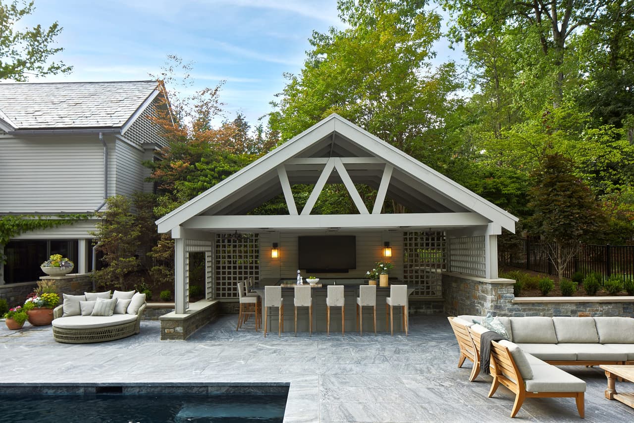 Covered outdoor bar and kitchenette beside the pool of a Westfield, NJ home, under a gabled roof on an exposed timber truss, built by Michael Robert Construction