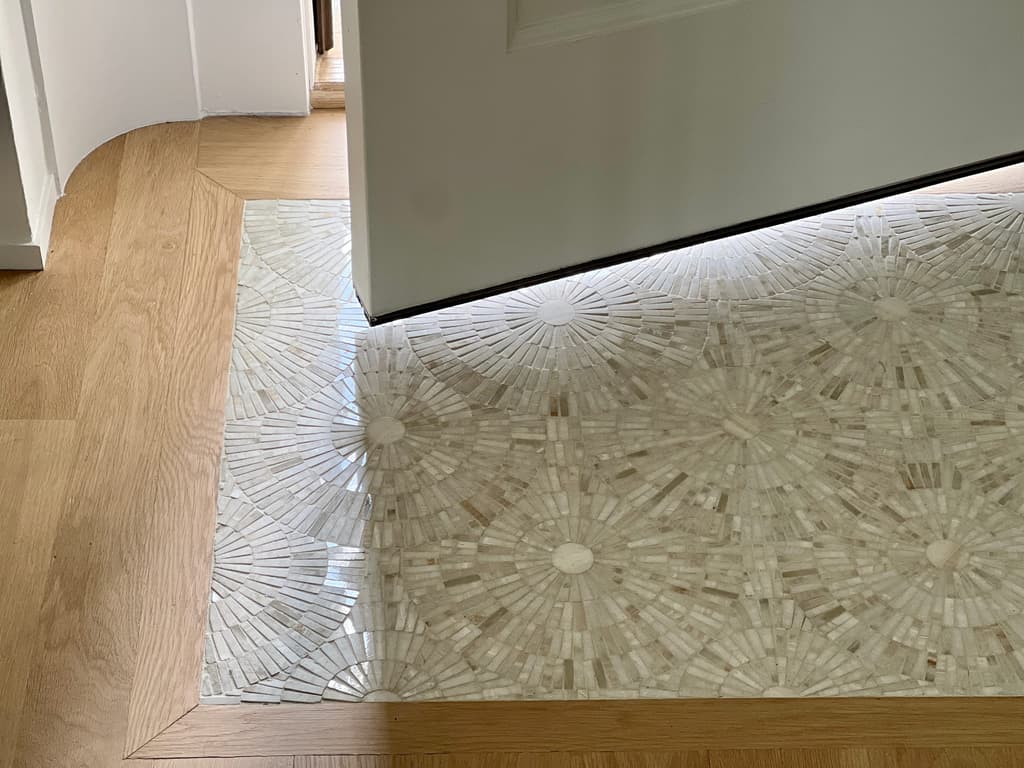 Mother-of-pearl mosaic inset into the oak floor of a Westfield, NJ foyer renovation, with a mitered wood border between the two