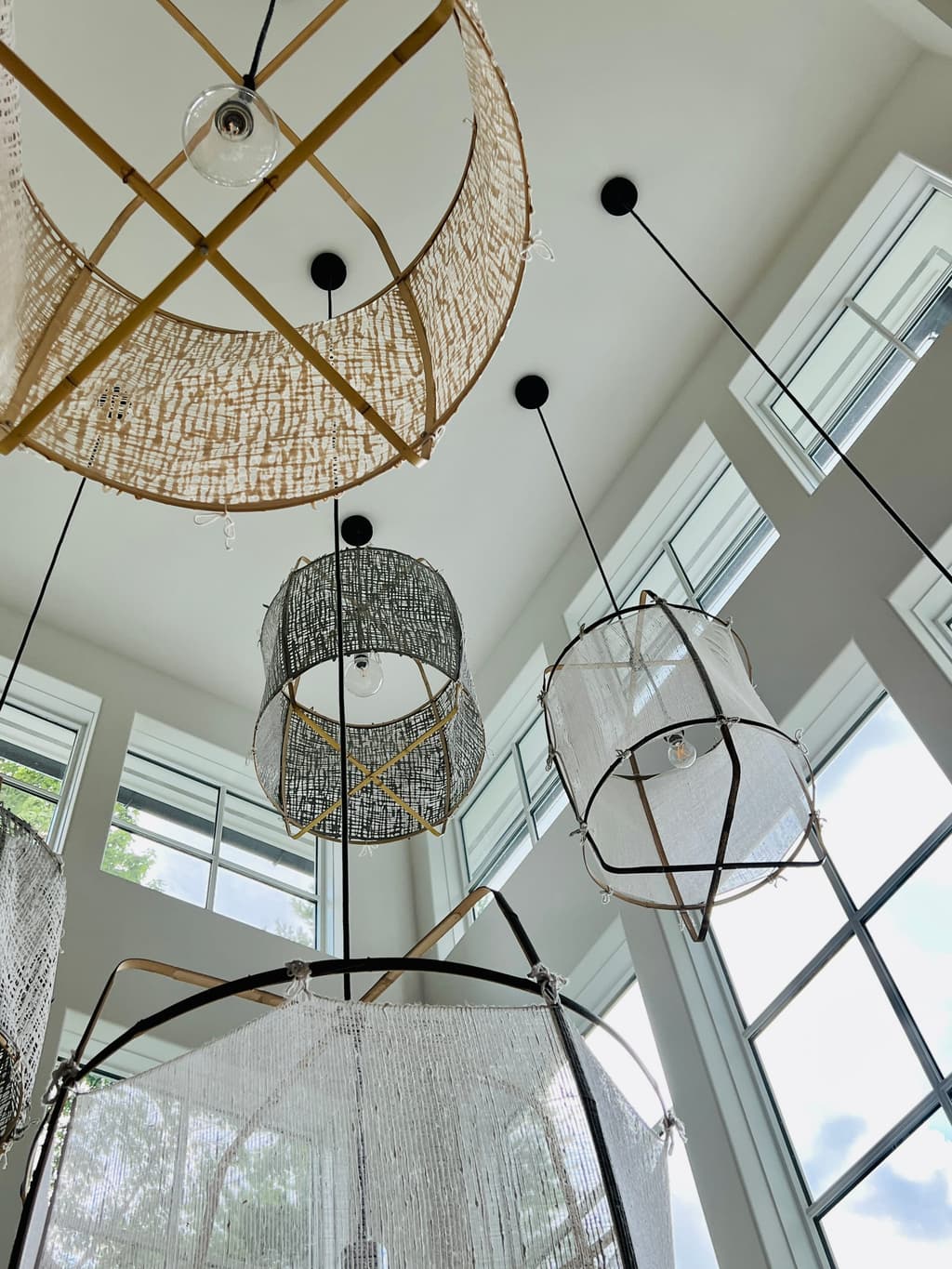 Woven and wire pendants hung at different heights in a double-height window tower of a Westfield, NJ home renovation, seen looking up
