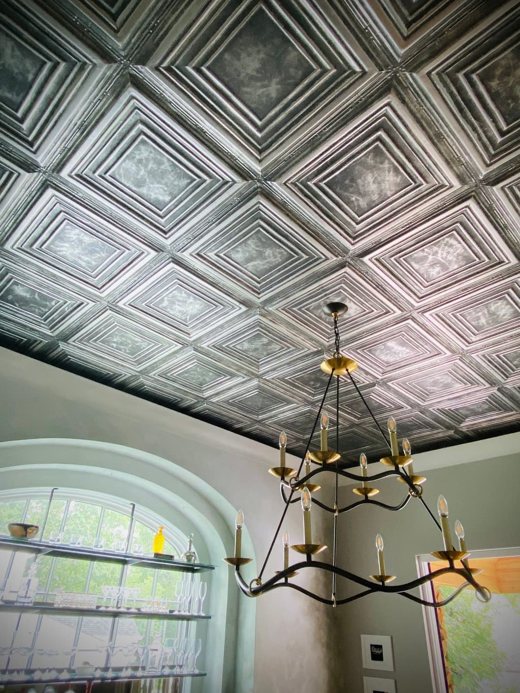Pressed-tin ceiling and an iron candle chandelier over the pub of a Westfield, NJ new-construction home, above an arched window