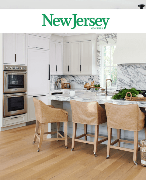 New Jersey Monthly masthead above a kitchen with double wall ovens, a marble island and leather stools, covering Michael Robert Construction