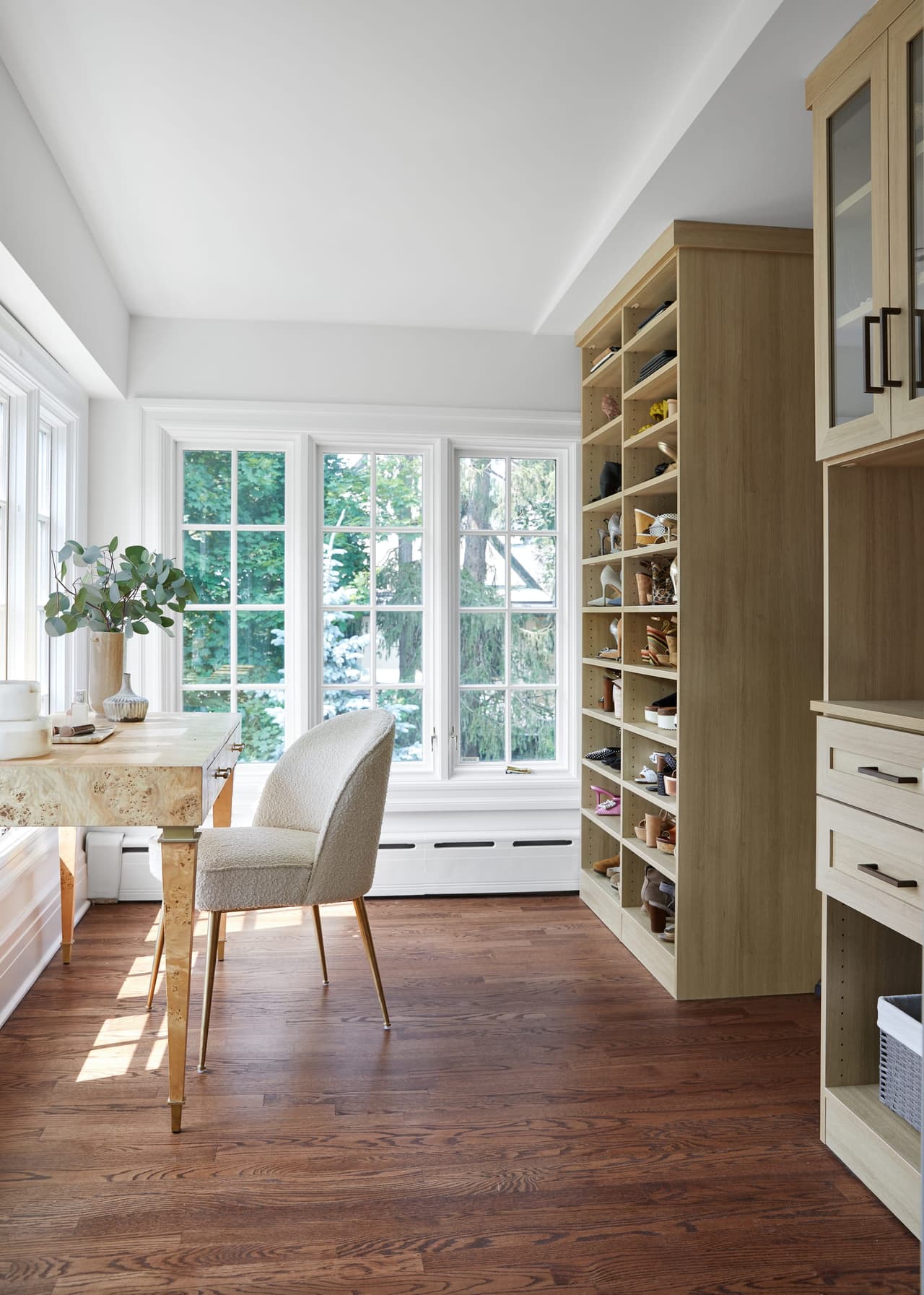 Dressing room in a historic Westfield, NJ home, with green built-in cabinetry, open shoe shelving and a chair at a window