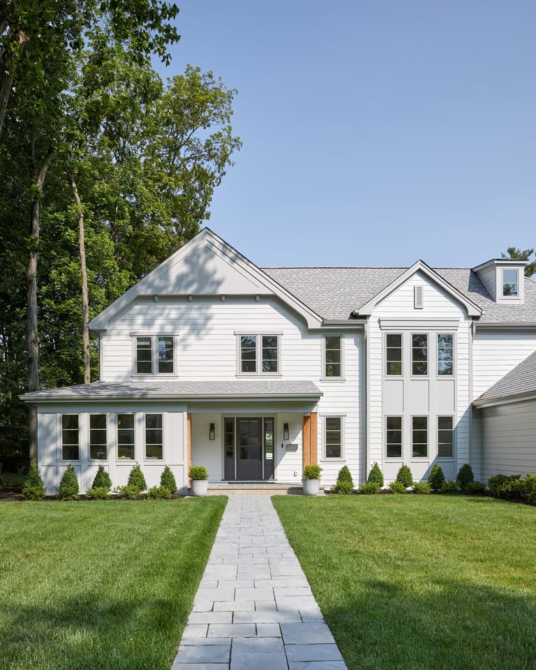 Front portico with cedar accents on a white Westfield, NJ home, approached by a paver walkway between clipped boxwood, by Michael Robert Construction