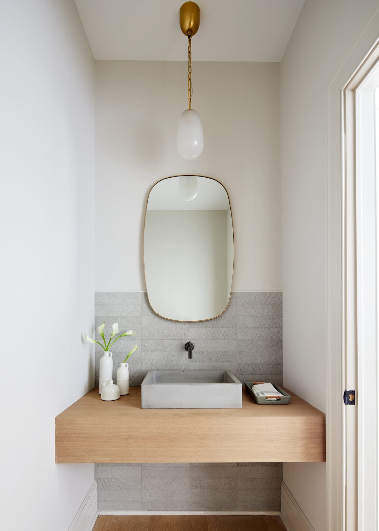 Powder room in a historic Westfield, NJ home with a floating wood console, a rectangular vessel sink, a wall-mounted tap and an arched brass mirror