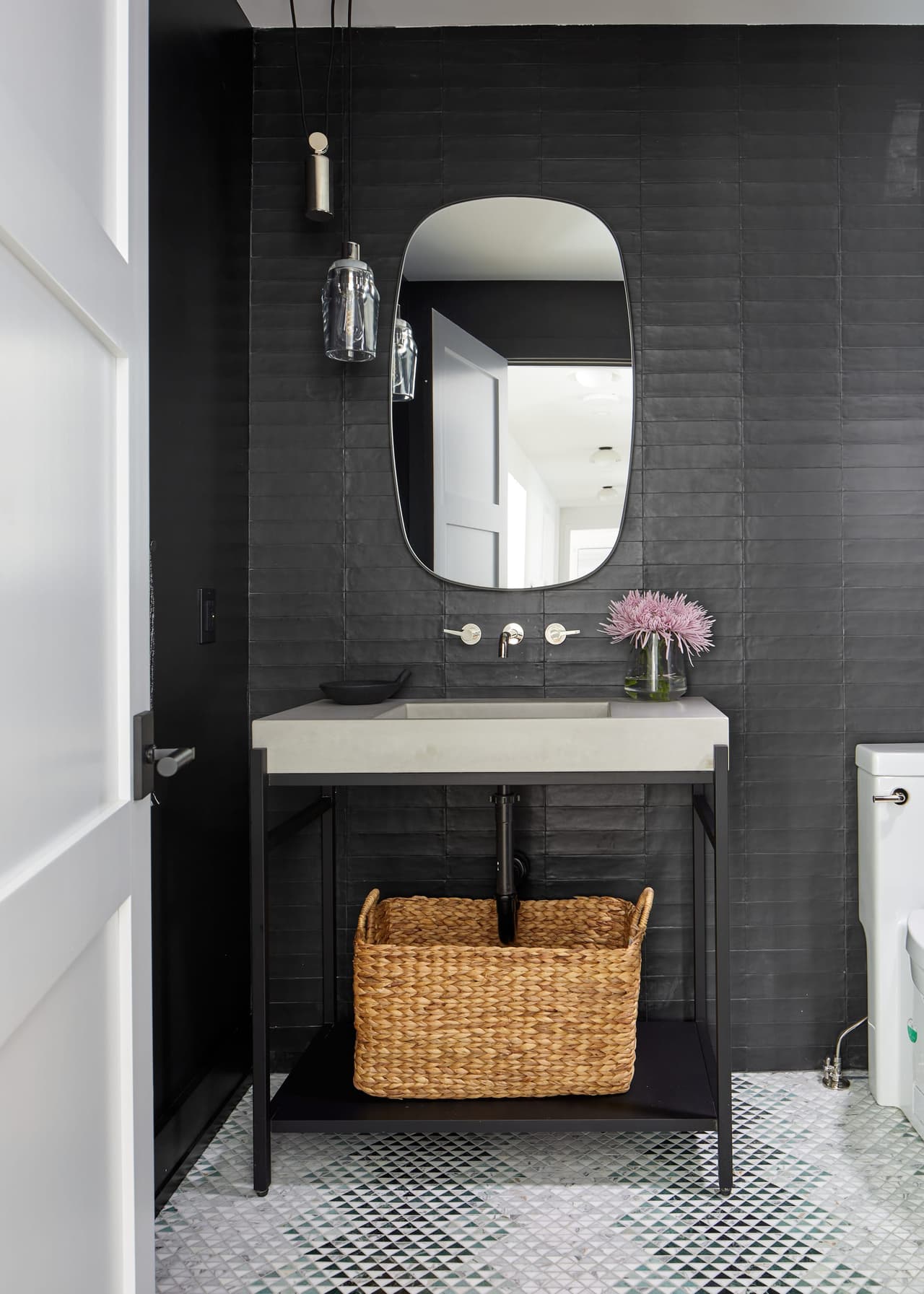 Powder room of a Westfield, NJ home renovation with black grasscloth walls, a floating stone basin over a woven basket and a marble mosaic floor