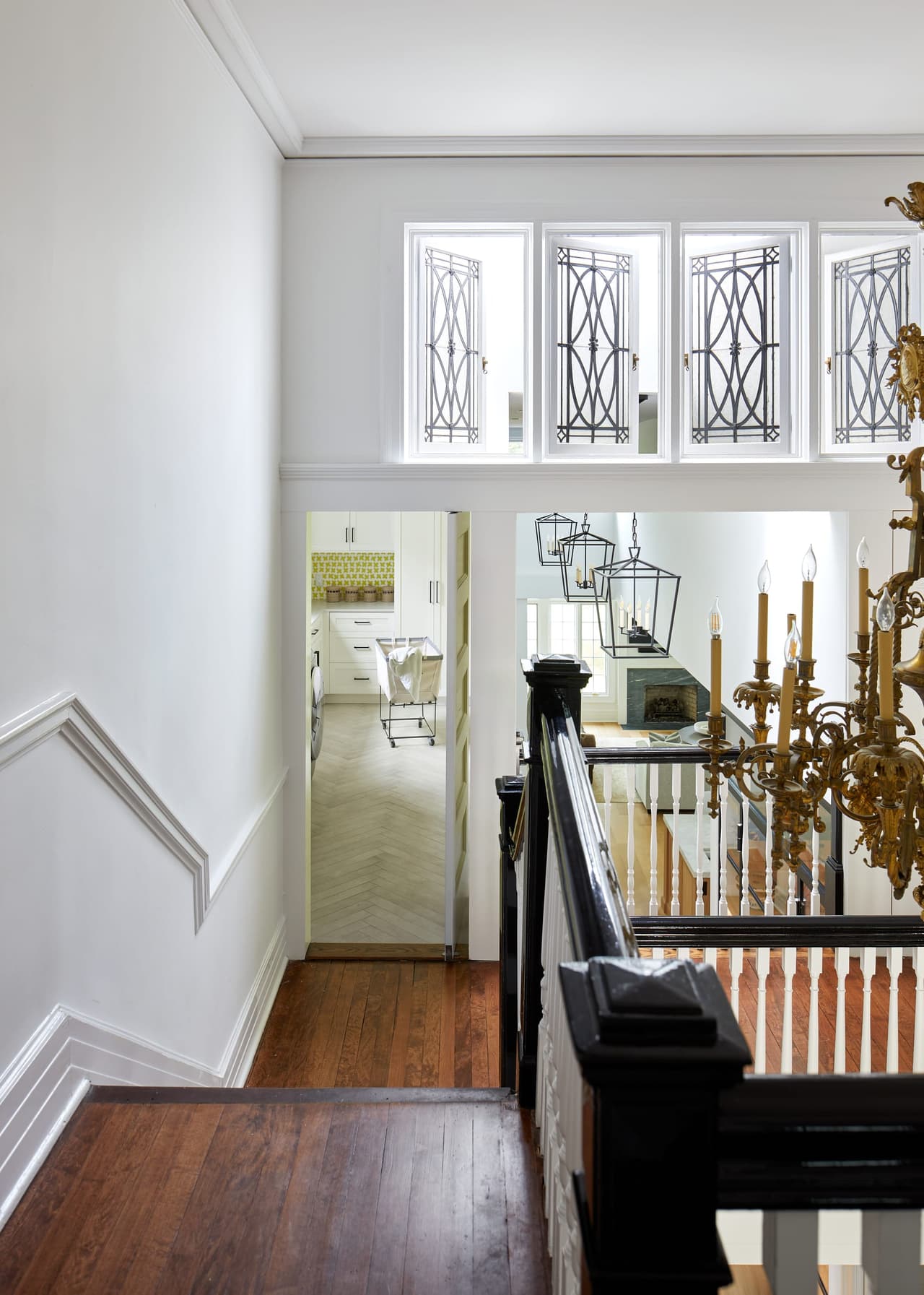 Upstairs hallway of a historic Westfield, NJ home, with leaded glass windows above the stair, paneled wainscot and a dark stained floor