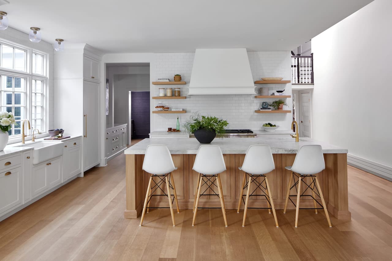 White kitchen in a historic Westfield, NJ home, with a plaster range hood, natural wood open shelves and a long island with molded stools, by Michael Robert Construction