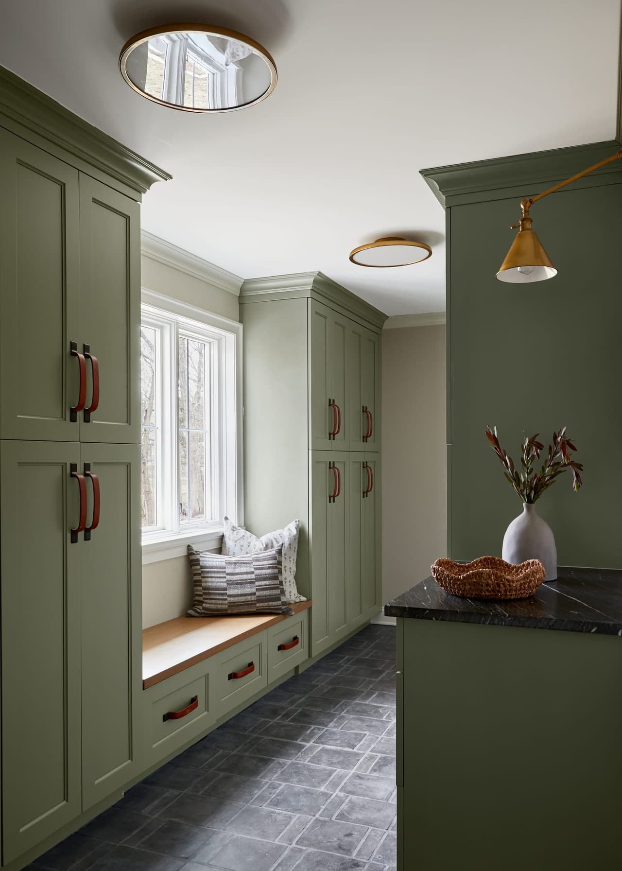 Mudroom in a Westfield, NJ home addition and renovation, with deep green floor-to-ceiling cabinetry, an oak bench under the window and a dark stone counter