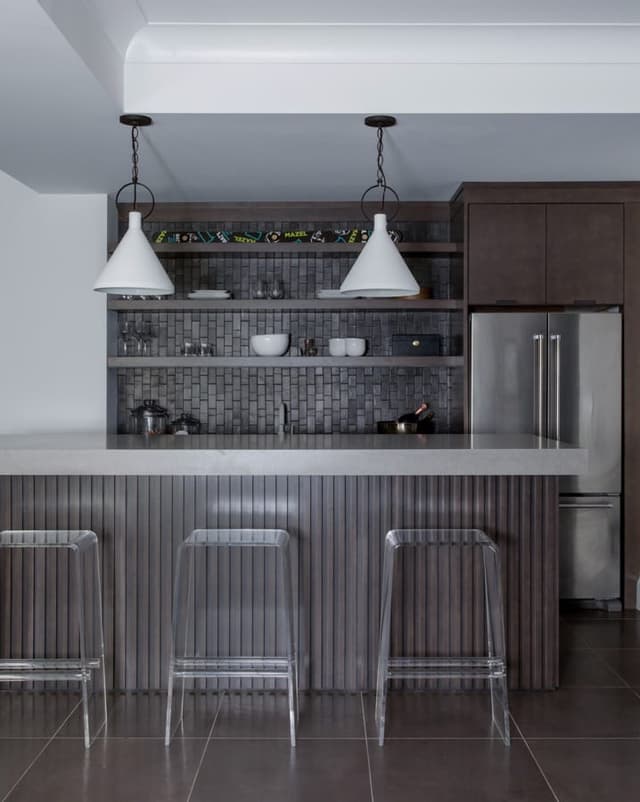 Basement bar in dark wood with two dome pendants, a tiled back wall and acrylic stools