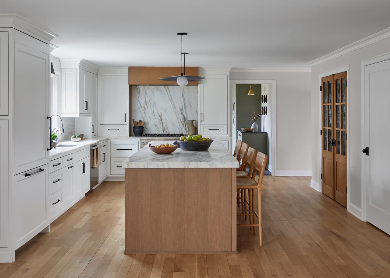 Kitchen of a Westfield, NJ home renovation with white cabinetry, a white oak island and a marble slab run up behind the range