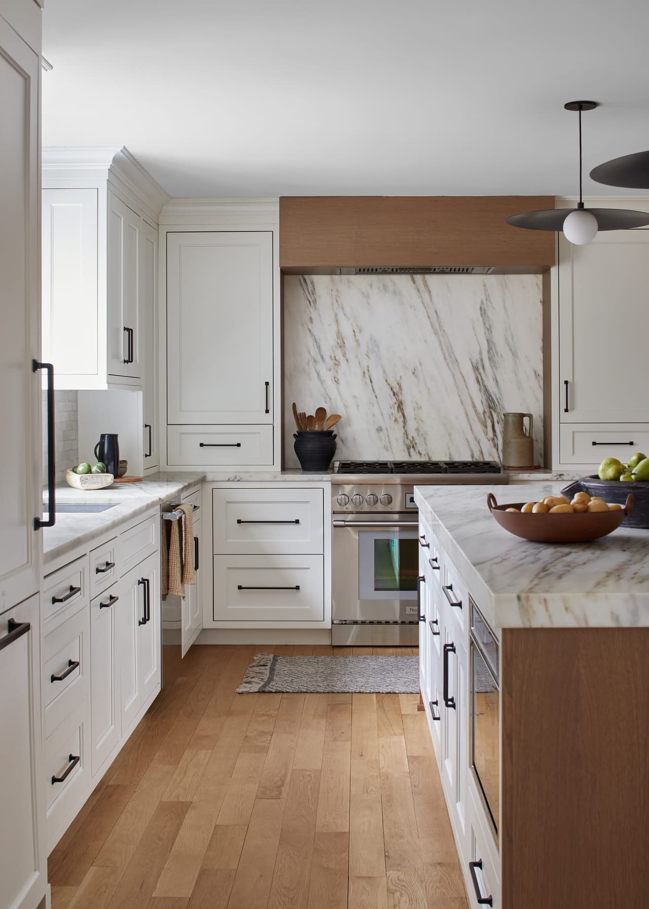 Range wall of a Westfield, NJ kitchen remodel, with the marble slab carried up between oak-faced cabinets and a tiled return