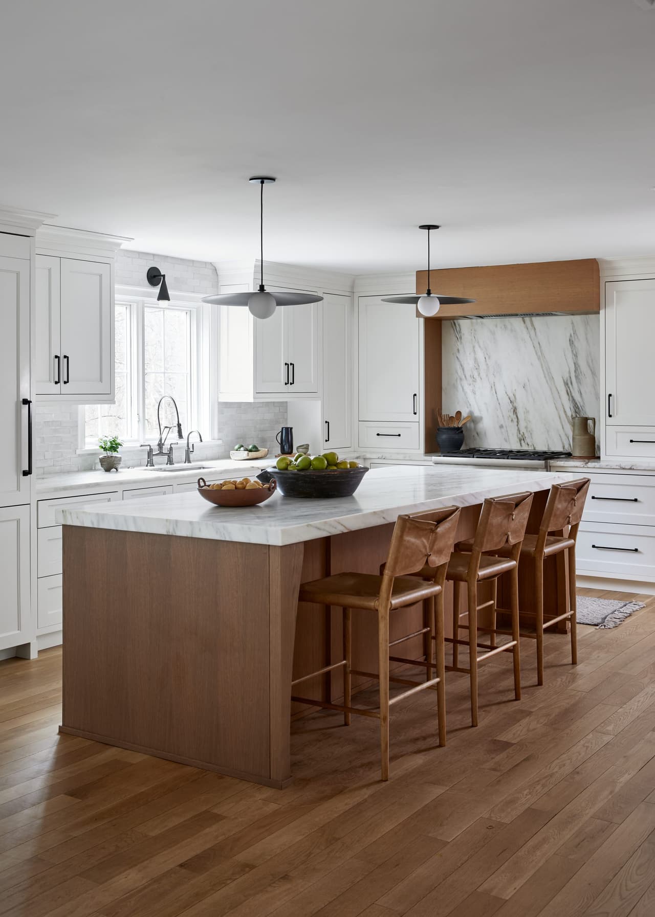 White oak island with a marble top and four spindle stools in a Westfield, NJ kitchen renovation, built by Michael Robert Construction