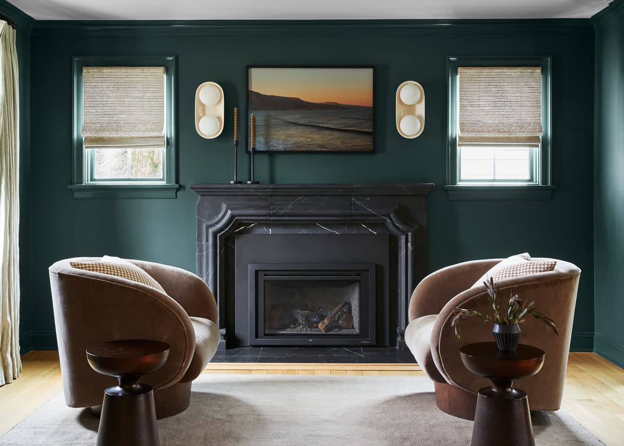 Lounge in a Westfield, NJ home renovation and addition, with deep green walls, a black marble fireplace surround and two swivel chairs facing it