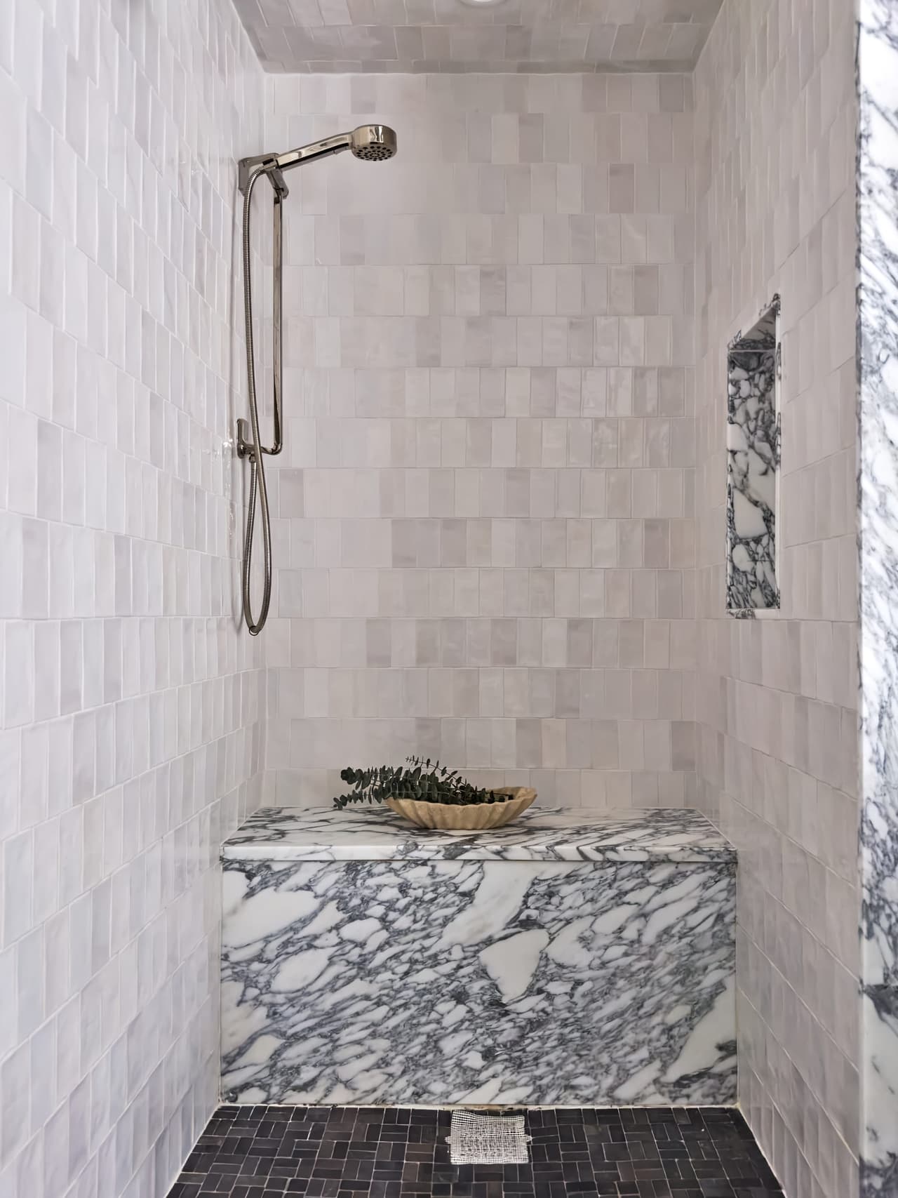Shower in a Westfield, NJ home renovation lined in zellige tile, with a solid marble bench and a slate pebble floor