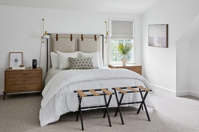 Guest bedroom in a Westfield, NJ home with a hanging upholstered headboard, a leather luggage bench and a window in the dormer