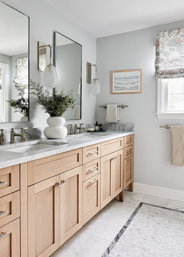Oak double vanity with a marble top, two mirrors and a mosaic marble border set into the floor in a Westfield, NJ primary bathroom renovation