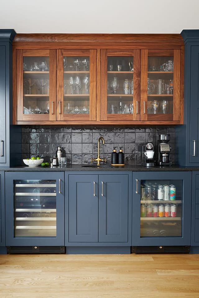 Walnut and navy custom bar in a Westfield, NJ home renovation, with glass-front upper cabinets, a dark glazed tile backsplash, a brass tap and a glass-door wine refrigerator
