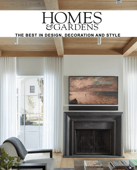 Homes & Gardens masthead above a beamed room with a black fireplace surround, from its coverage of Michael Robert Construction