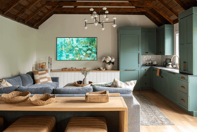 Family room under a vaulted plank ceiling in a Westfield, NJ barn renovation by Michael Robert Construction, with sage cabinetry, a sectional at the fireplace and a long window table
