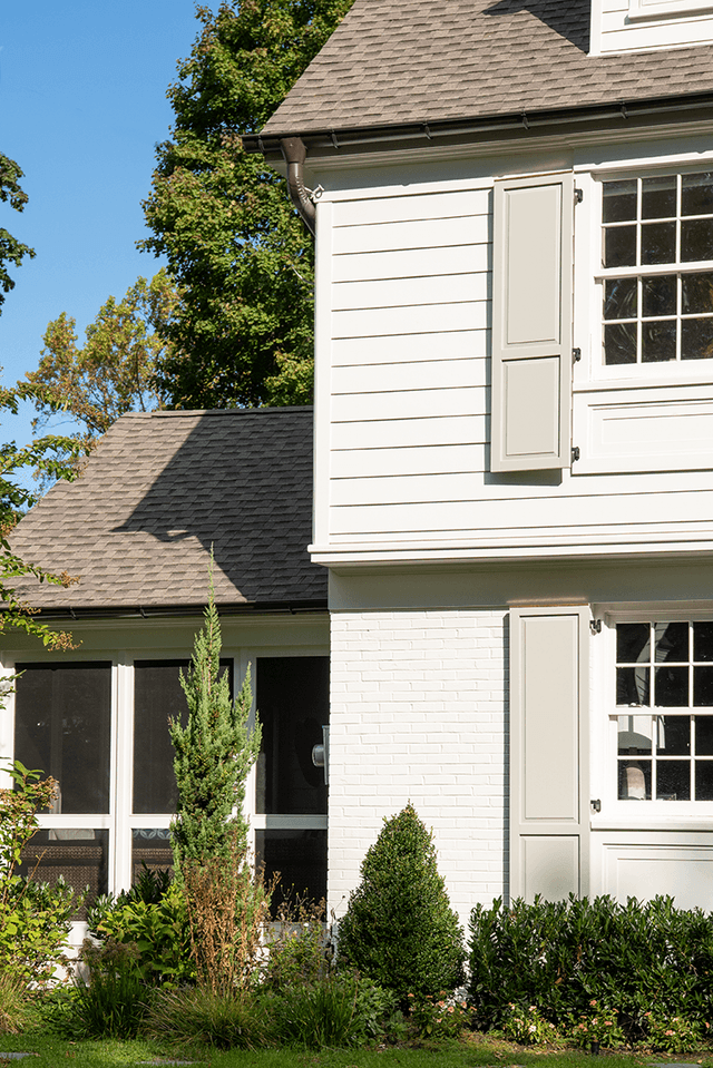Copper-trimmed bay roof and custom shutters on the painted brick of a Summit, NJ exterior renovation, built by Michael Robert Construction