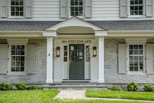 Front elevation of a Westfield, NJ renovation with a pedimented portico over a green front door, louvered shutters and a stone base course