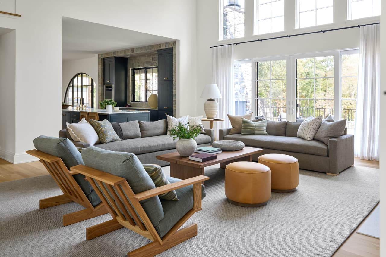 Family room of a Mendham, NJ home with two sectionals, wooden lounge chairs and arched openings in the wall opposite the windows