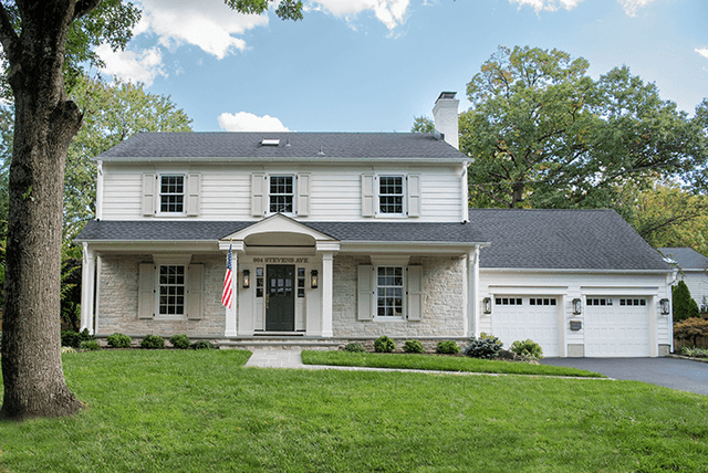 Full front exterior of a white colonial remodel in Westfield, NJ, with a columned entry porch, dark shutters and an attached garage