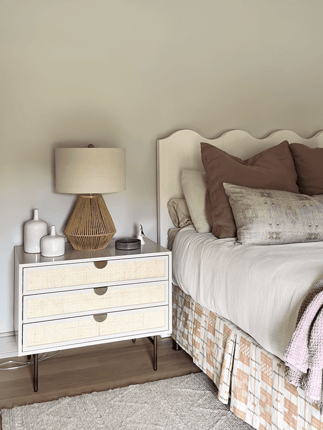 Child's bedroom in a Mendham, NJ home, with a scalloped upholstered headboard, a cane-fronted nightstand and a patchwork bed skirt