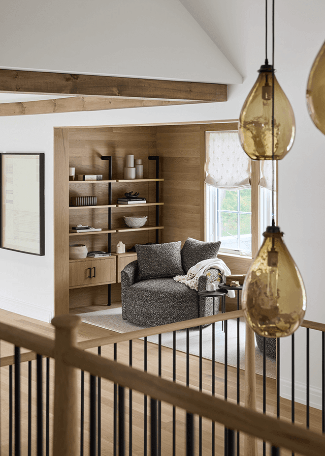 Reading nook off a Mendham, NJ upstairs hall, lined in oak shiplap with built-in shelves, a round swivel chair and amber pendants hung in front