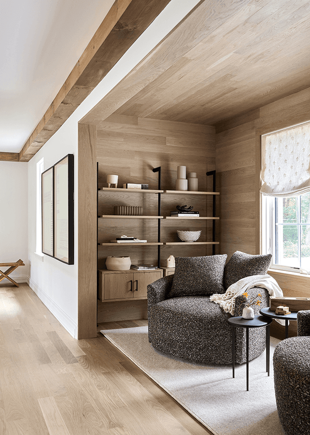 Oak shiplap nook with built-in shelving under a beam in a Mendham, NJ hall, with a round boucle swivel chair at the window