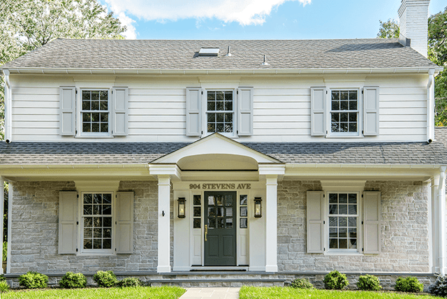 Westfield, NJ home exterior renovation seen from the lawn, with a columned porch, a stone first storey and custom trim throughout, by Michael Robert Construction