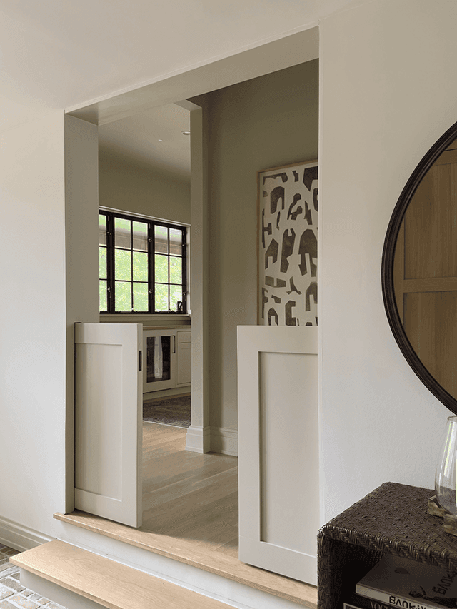 Mudroom of a Mendham, NJ home with a dog door cut into the custom cabinetry, a round mirror and a view through to the glazed back hall