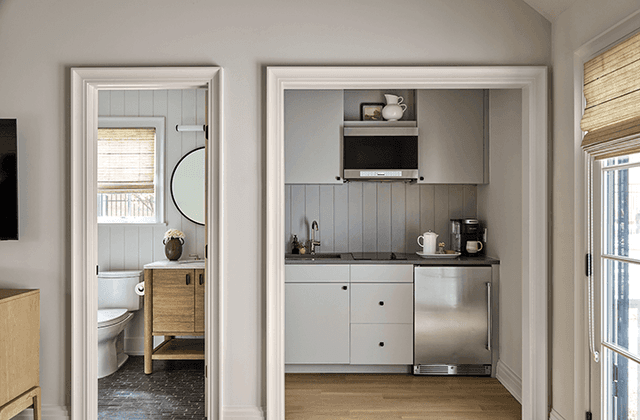 Kitchenette and shower room inside the poolhouse of a Mendham, NJ home, finished in shiplap with an oak washstand and a round mirror