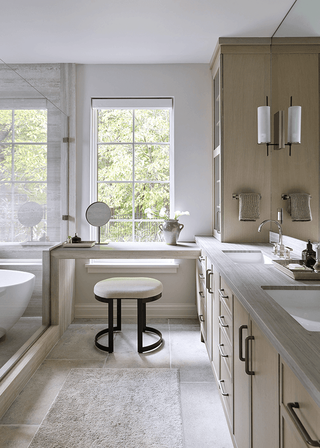 Custom double vanity in the primary bathroom of a Mendham, NJ home, with a dressing table between the basins and fluted sconces at the mirrors