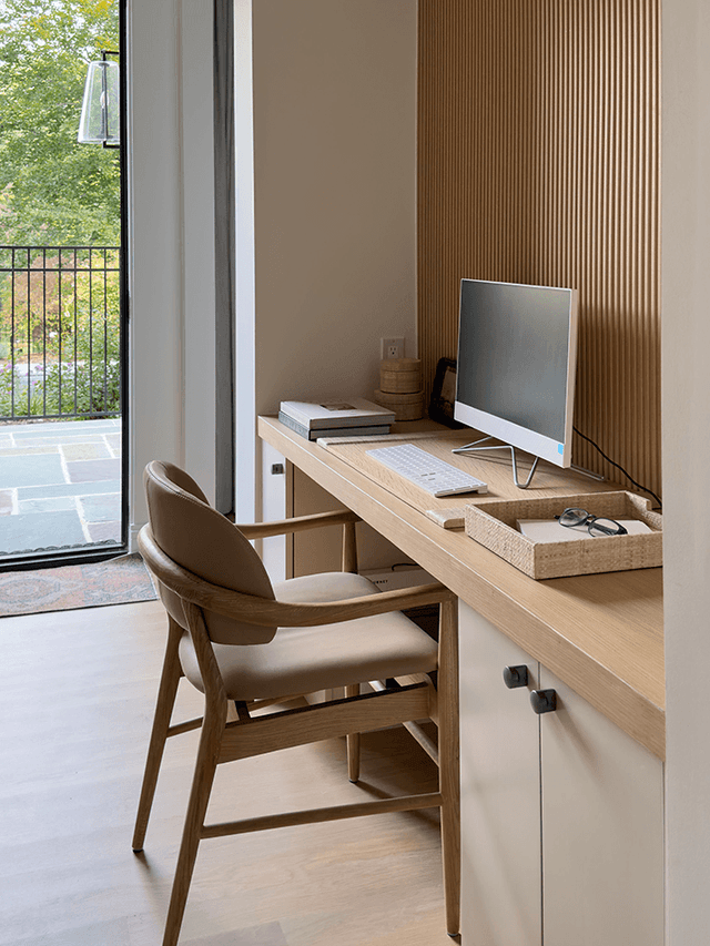 Built-in desk against a fluted oak wall in the primary suite of a Mendham, NJ home, beside glass doors onto the terrace