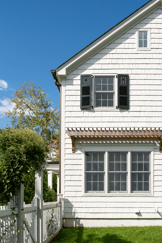 Side elevation of a Westfield, NJ exterior renovation, with white shingles, black shutters and a cedar pergola along the lower wall