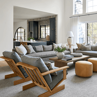 Living room with an arched cased opening through to the kitchen, slatted wood armchairs and a pale sectional