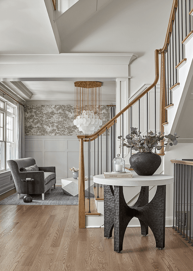 Foyer of a Westfield, NJ custom home, with a white stair and oak handrail, a sculptural round table and a lantern overhead