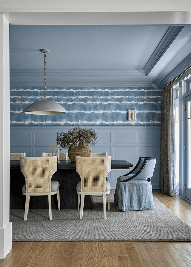 Dining room in a Westfield, NJ custom home, with blue patterned walls, woven chairs and a skirted host chair at the table end