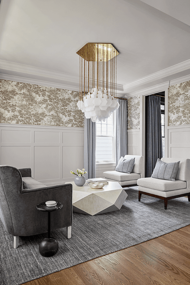 Lounge in a Westfield, NJ new build, with paneled wainscot under a patterned paper and a cascading glass chandelier over the seating