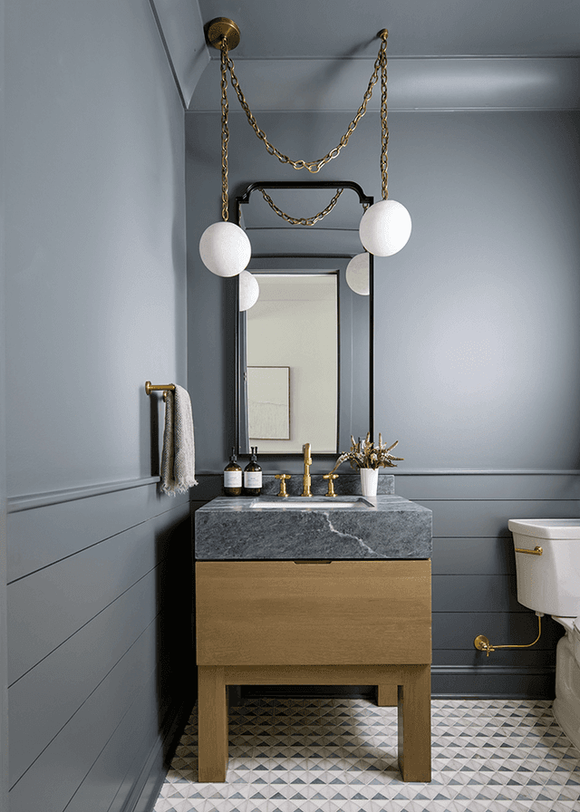 Powder room in a Westfield, NJ new-construction home, with gray paneled walls, an oak washstand under a stone top and a chain-hung modern light over the mirror