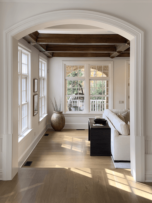 Arched doorway through to the family room of a Summit, NJ remodel, framing the beamed ceiling and the windows beyond