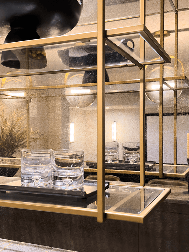 Brass and glass hanging bar cabinet over a Summit, NJ counter, with glasses and a tray below it