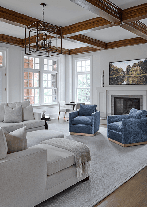 Living room of a Summit, NJ renovation under a stained coffered ceiling, with a sectional, blue swivel chairs and an iron lantern overhead