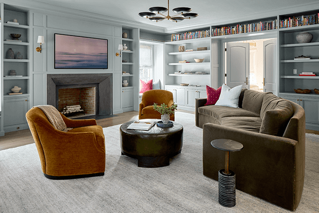 Living room of a Summit, NJ renovation painted out in one soft blue, with built-in bookshelves either side of the fireplace and velvet swivel chairs