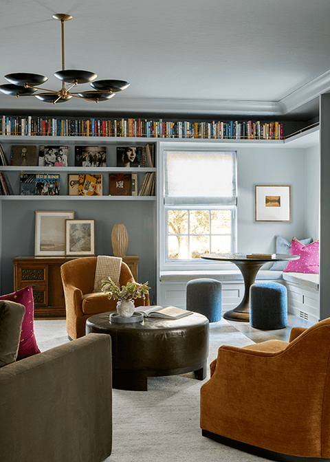 Library with floor-to-ceiling built-in bookshelves, a tan leather armchair and a round ottoman, in Summit, NJ