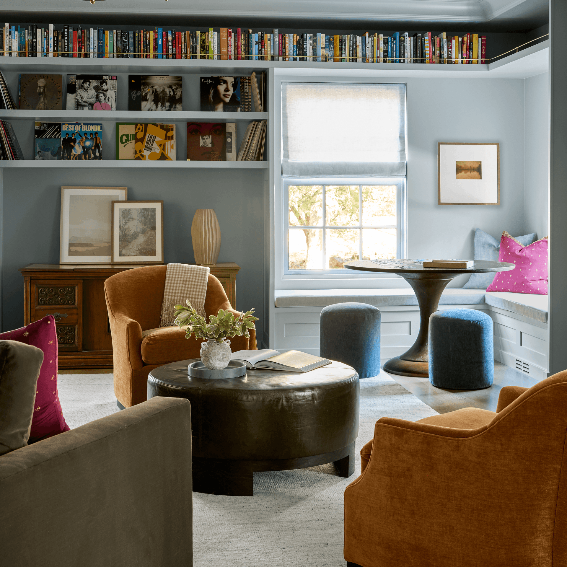 Blue-gray lounge with a picture-rail book ledge, vinyl record shelving, rust velvet armchairs, a round leather ottoman and a window-seat banquette in Summit, NJ