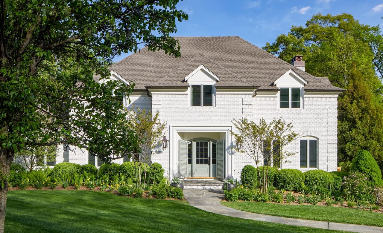 Full front exterior of a classic painted white brick home with a blue front door after renovation in Mountainside, NJ, by Michael Robert Construction