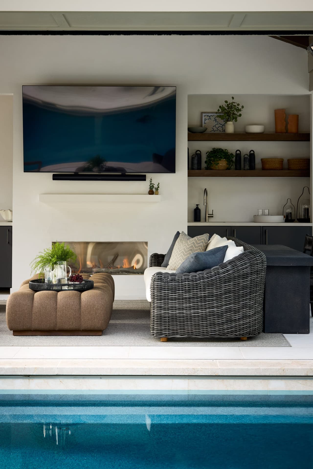 Covered outdoor entertainment pavilion with linear fireplace wall mounted television built in wet bar and custom cabinetry in a indoor and outdoor living project in Westfield, NJ
