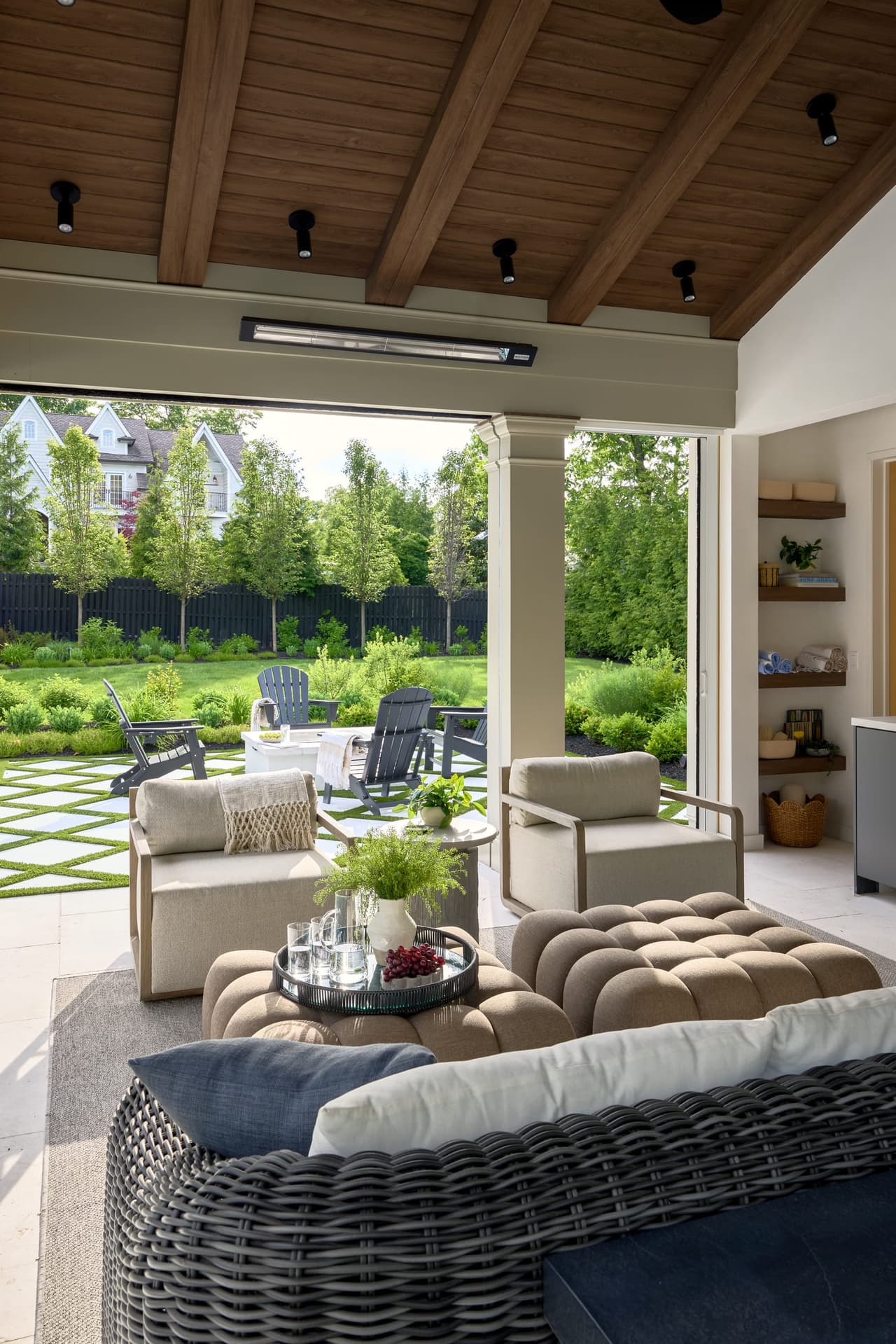 Covered pool pavilion with exposed wood beams integrated heaters recessed lighting and open views of a landscaped backyard in a indoor and outdoor living project in Westfield, NJ